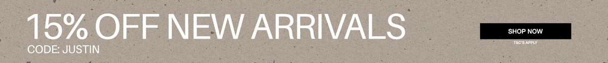 A promotional banner with a textured light gray background featuring the text '15% OFF NEW ARRIVALS' in large white letters, 'CODE: JUSTIN' on the left, and a black 'SHOP NOW' button on the right.