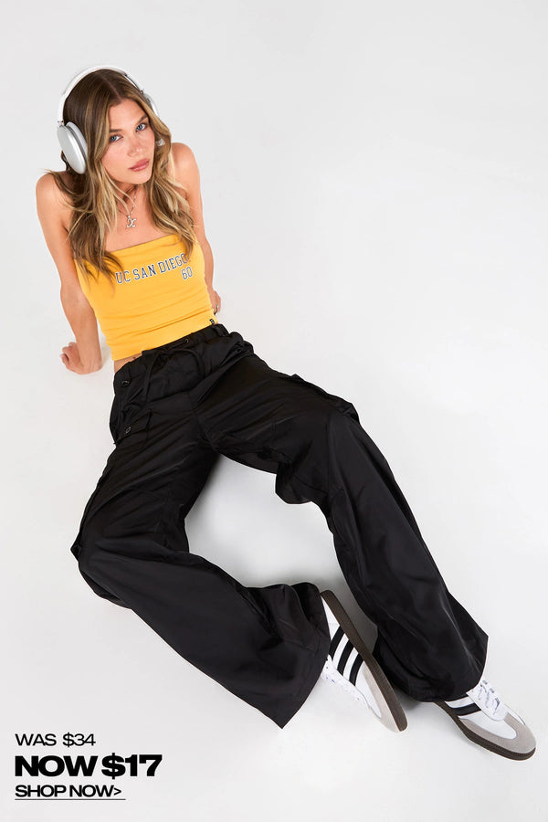 Woman wearing a yellow tank top and black pants sitting on a white background with promotional text.