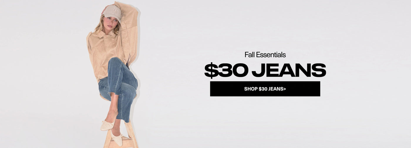 Person wearing a beige sweater and blue jeans sitting on a white background with text promoting $30 jeans.