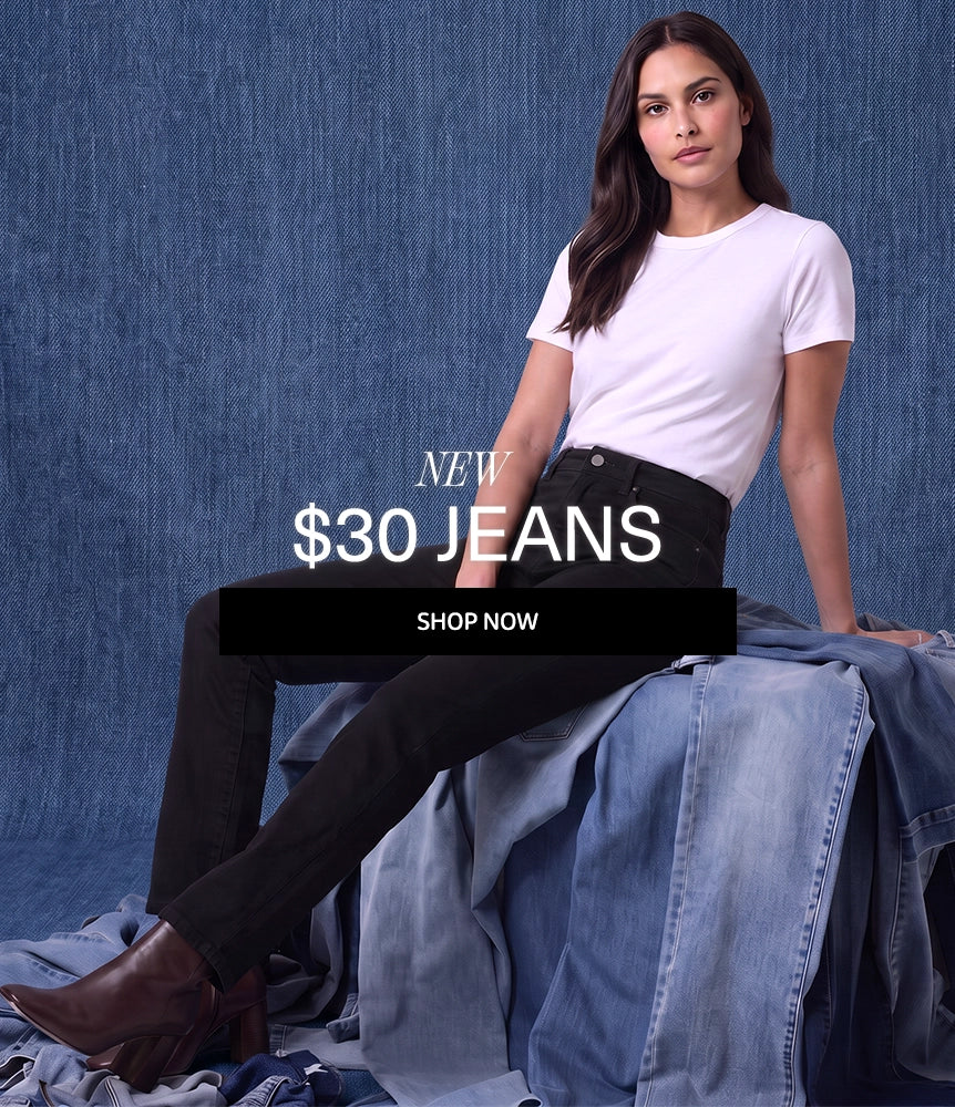 A woman models a pair of black high-waisted jeans with a white t-shirt and brown boots, posed on a pile of blue denim against a blue textured backdrop. A black banner with the text 'NEW $30 JEANS SHOP NOW' is overlaid in the center.