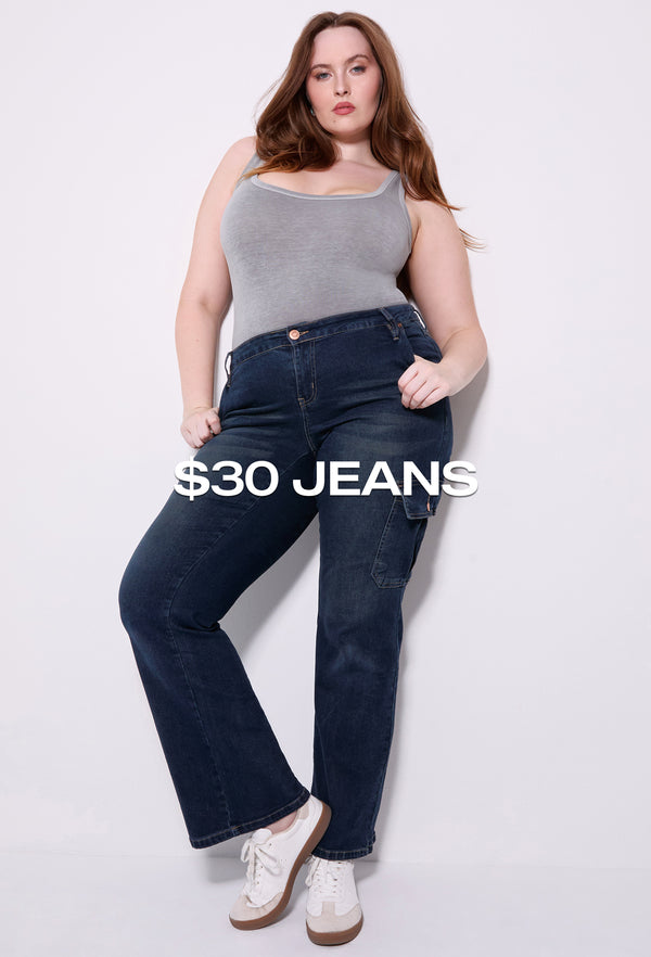 Woman wearing dark blue plus size jeans with a grey tank top, featured on the $30 jeans collection from YMI Jeans.