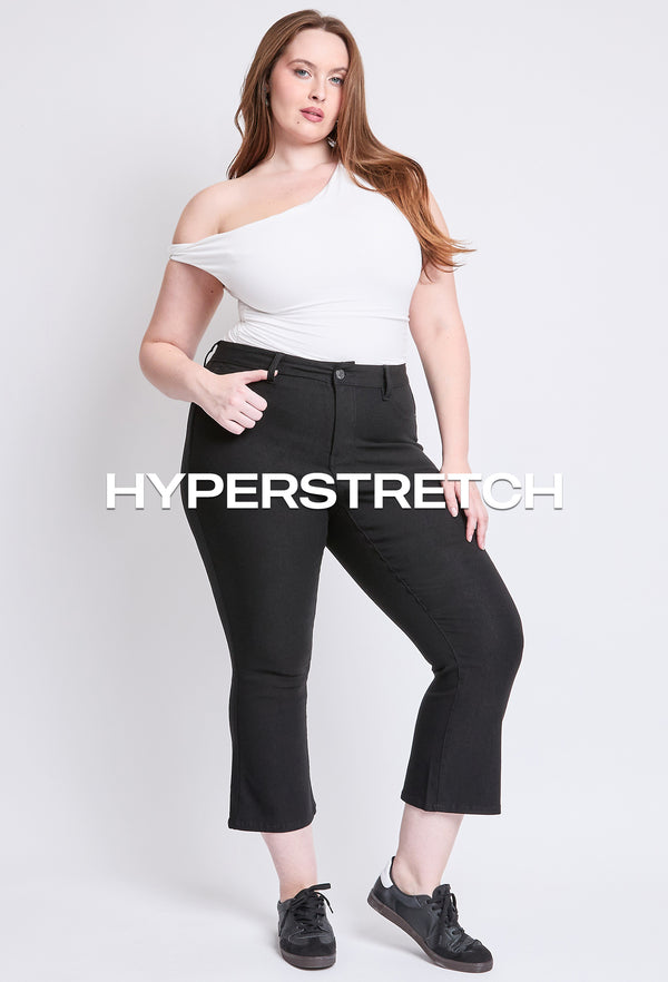 Model wearing black hyperstretch jeans and a white off-shoulder top, showcasing plus size jeans collection.